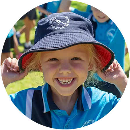 A South Halls Head student in a school bucket hat smiling on the school grounds